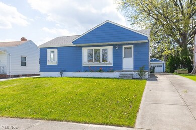 View of front of home featuring an outdoor structure, a front yard, and a garage