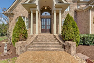The home's front entrance, with its handsome columns, graceful arched cover, contemporary light fixture and tall wood doors, makes a grand first impression. 