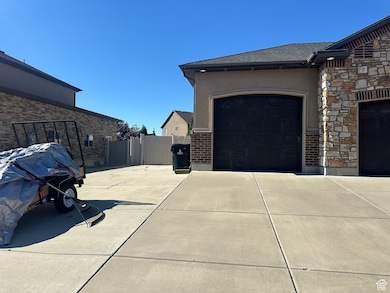 View of side of property featuring driveway, stucco siding, a garage, and stone siding