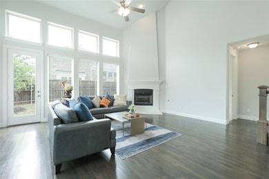 Living room featuring a towering ceiling, dark wood-type flooring, ceiling fan, and a fireplace
