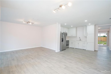 Kitchen featuring stainless steel fridge,  stove, light countertops, open floor plan, and light wood-style flooring
