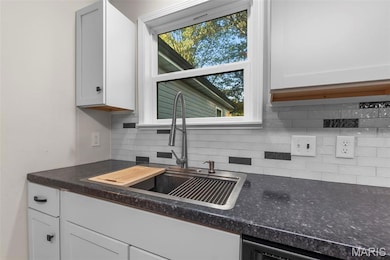 Crisp and contemporary kitchen with shaker-style cabinetry and a deep stainless sink with a pull-down faucet, sitting perfectly beneath a sunny window.
