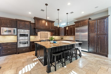 Gourmet kitchen is equipped with high end Viking appliances including a built-in fridge, gas range, and double ovens. Note the large island which features storage beneath.