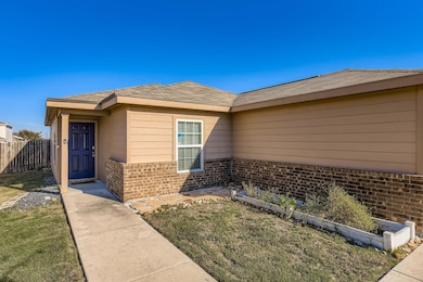 View of exterior entry featuring a shingled roof and brick siding