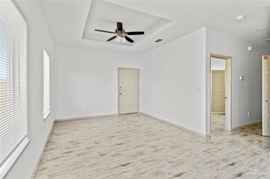Unfurnished room with a raised ceiling, light wood finished floors, and ceiling fan