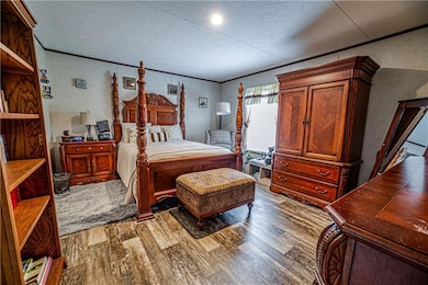 Bedroom with wood finished floors, a textured ceiling, and ornamental molding