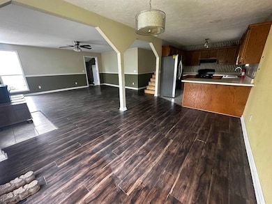 Kitchen featuring open floor plan, refrigerator with ice dispenser, a sink, dark wood finished floors, and a textured ceiling