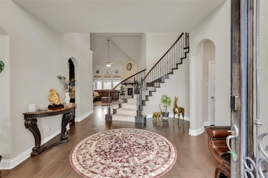 Foyer entrance featuring arched walkways, stairs, dark wood finished floors, a high ceiling, and ceiling fan