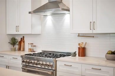 Kitchen featuring white cabinetry, wall chimney r
