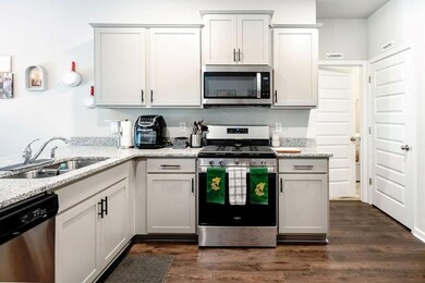 Kitchen with appliances with stainless steel finishes, light stone countertops, and dark wood finished floors