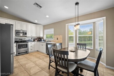 Kitchen featuring decorative backsplash, appliances with stainless steel finishes, light tile patterned flooring, lofted ceiling, and hanging light fixtures