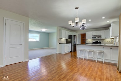 kitchen with dark countertops, a chandelier, light wood-type flooring, appliances with stainless steel finishes, and a peninsula