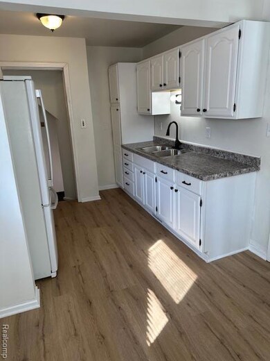 Kitchen featuring dark countertops, fridge, white cabinetry, and light wood-type flooring