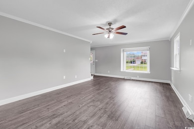 Unfurnished room featuring crown molding, ceiling fan, dark wood finished floors, and a textured ceiling