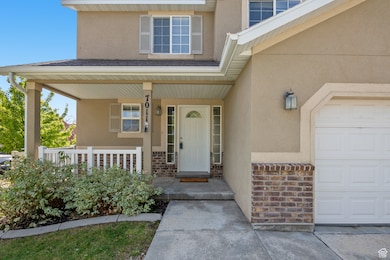 Entrance to property featuring a garage, stucco siding, and covered porch