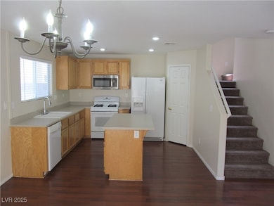 Kitchen with white appliances, a sink, dark wood-s