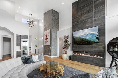 Living room with wood finished floors, a high ceiling, a fireplace, a chandelier, and recessed lighting