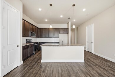 Kitchen featuring stainless steel appliances, dark brown cabinetry, pendant lighting, recessed lighting, and an island with sink