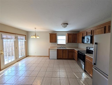 Kitchen featuring white appliances, light countertops, a chandelier, decorative light fixtures, and light tile patterned floors
