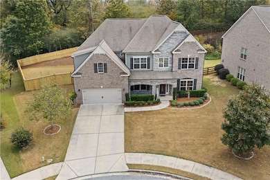 View of front facade with concrete driveway, covered porch, a garage, roof with shingles, and stone siding