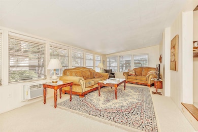 Sunroom featuring a healthy amount of sunlight, a wall mounted air conditioner, and vaulted ceiling
