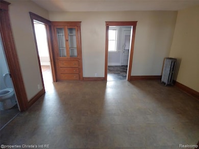 Empty room with baseboards and radiator heating unit
