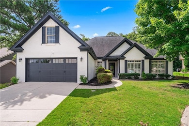 View of front of property featuring brick siding, driveway, a front lawn, an attached garage, and roof with shingles