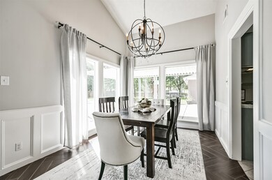 Adjacent to the family room and with direct access to the kitchen, this dining room features a vaulted ceiling with a stylish spherical chandelier, block paneling, wood-look tile floors, and undivided cased windows with impressive backyard views.