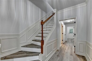 Stairway with a decorative wall, wainscoting, wood finished floors, and ornamental molding