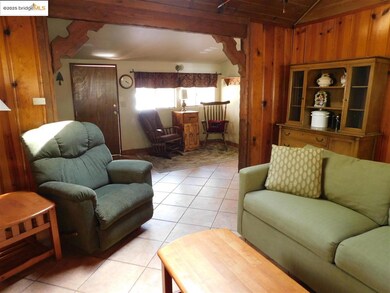 Tiled living room with wood walls and lofted ceiling with beams