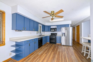 Kitchen with black appliances, blue cabinets, open
