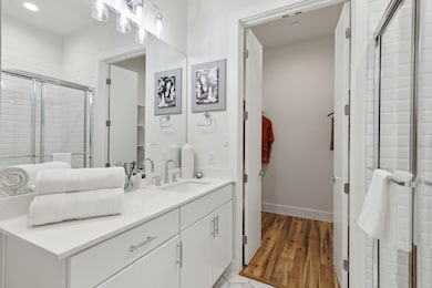 Bathroom featuring a shower stall, vanity, and light wood finished floors