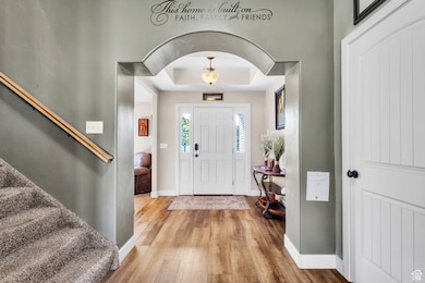 Entrance foyer featuring a tray ceiling, wood finished floors, and stairway