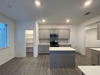 Kitchen with light countertops, stainless steel appliances, gray cabinets, and dark wood finished floors