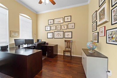 Natural light flows through the double French doors and arched windows in the study highlighting the crown molding and hardwood floors.