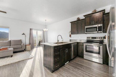 Kitchen featuring stainless steel appliances, open floor plan, staggered knotty alder cabinets, granite countertops, and laminate floors.