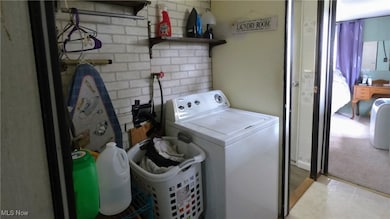 Laundry room with washer / clothes dryer and brick wall