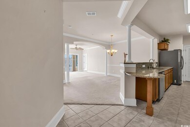 Kitchen featuring light stone counters, light tile patterned floors, light carpet, decorative light fixtures, and ornamental molding