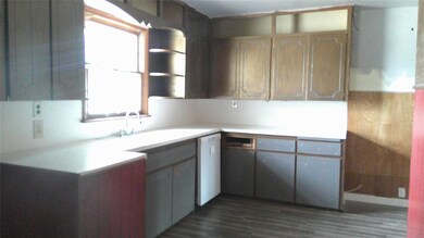 Kitchen featuring white dishwasher and dark wood-t