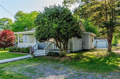 View of front of house with a garage, a front yard, covered porch, and an outdoor structure