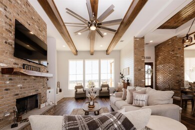 Living area with beam ceiling, a fireplace, brick