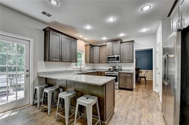 Updated Kitchen featuring appliances with stainless steel finishes, a peninsula, tasteful backsplash, light wood finished floors, and recessed lighting