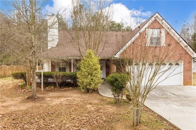 View of front of property with brick siding, a garage, concrete driveway, and a chimney
