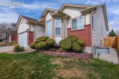 View of front facade with fence, a front lawn, brick siding, an attached garage, and driveway