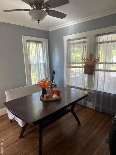 Dining room featuring dark wood-style floors, a ceiling fan, and ornamental molding