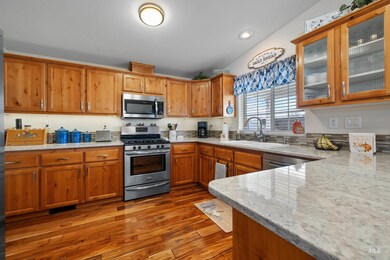 Kitchen featuring stainless steel appliances, light stone countertops, dark wood-style floors, and brown cabinetry