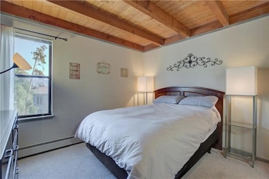 Bedroom featuring a baseboard heating unit, beamed