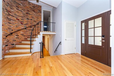 Foyer featuring brick wall, light wood-style floors, and stairway