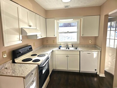 Kitchen with a textured ceiling, white appliances,