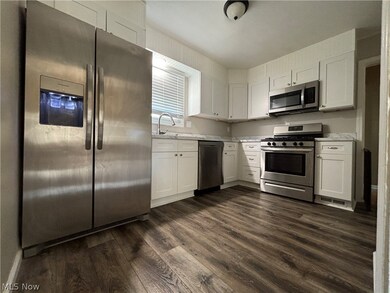 Kitchen with appliances with stainless steel finishes, white cabinetry, sink, and dark wood-type flooring